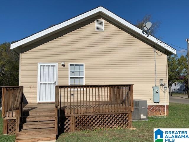 rear view of house with a yard, cooling unit, and a deck