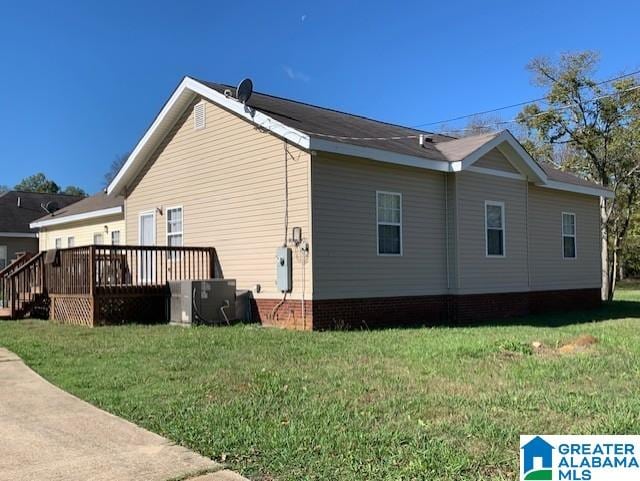 view of side of home with a wooden deck, a yard, and central AC unit