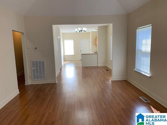 spare room with lofted ceiling, dark wood-type flooring, and a chandelier