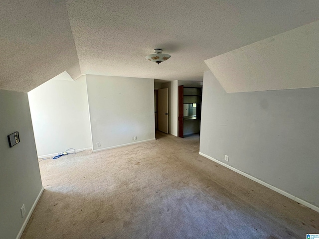 additional living space with a textured ceiling, lofted ceiling, and light carpet