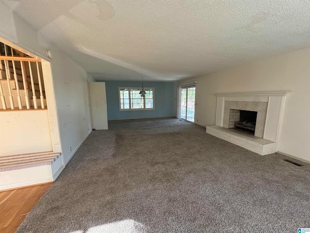 unfurnished living room with carpet flooring, a brick fireplace, a textured ceiling, vaulted ceiling, and a chandelier