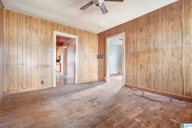 unfurnished room featuring hardwood / wood-style flooring, ceiling fan, and wooden walls