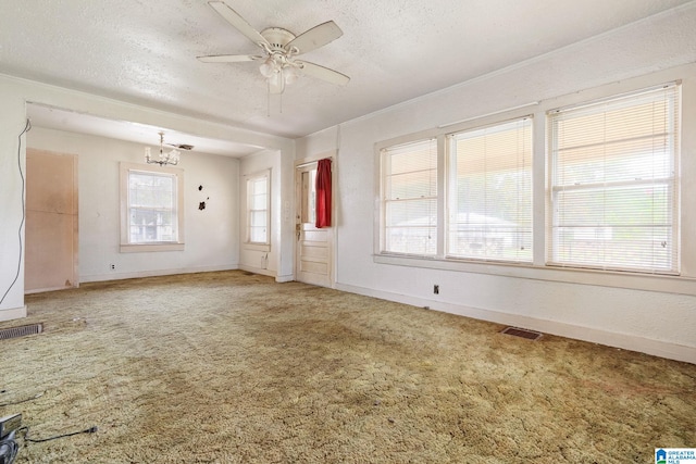 unfurnished living room with carpet flooring, ceiling fan with notable chandelier, and a textured ceiling