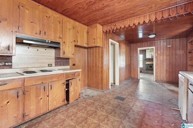 kitchen featuring tasteful backsplash, white stovetop, wooden ceiling, a fireplace, and wood walls