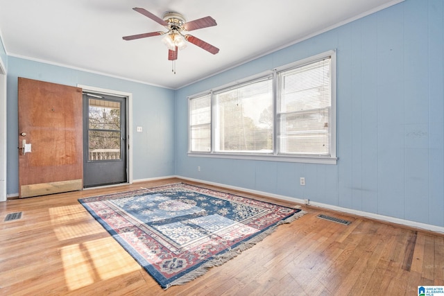 empty room featuring hardwood / wood-style flooring, ceiling fan, a healthy amount of sunlight, and crown molding