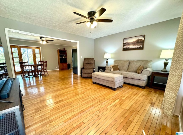 living room featuring ceiling fan, light hardwood / wood-style floors, and a textured ceiling