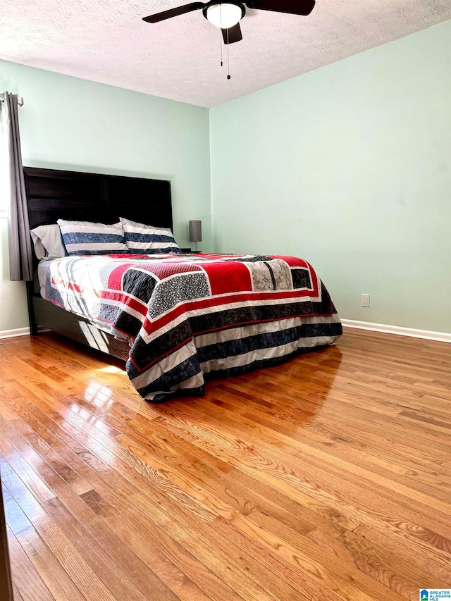 bedroom featuring ceiling fan, a textured ceiling, and hardwood / wood-style flooring