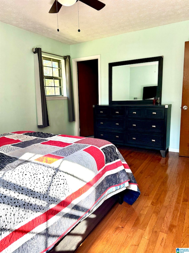 bedroom with ceiling fan, dark hardwood / wood-style flooring, and a textured ceiling