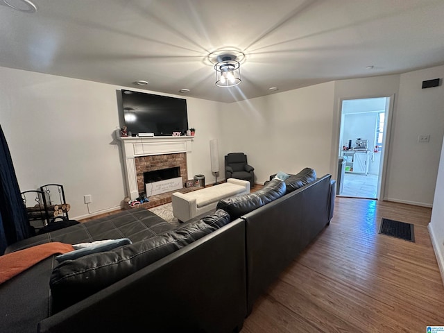 living room with dark wood-type flooring and a brick fireplace