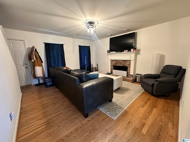 living room with a brick fireplace and hardwood / wood-style flooring