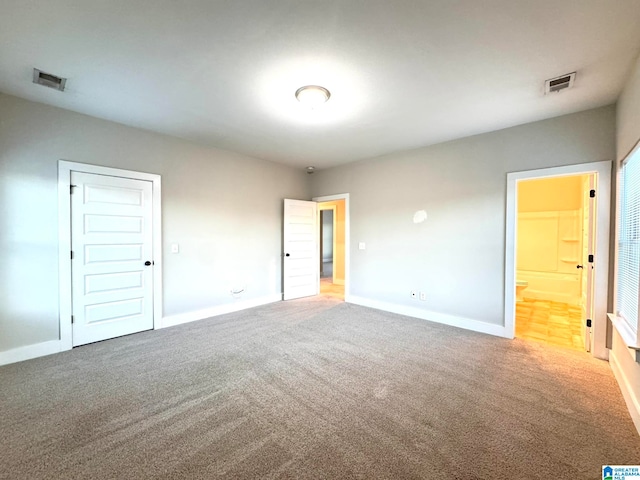 unfurnished bedroom with carpet flooring and connected bathroom