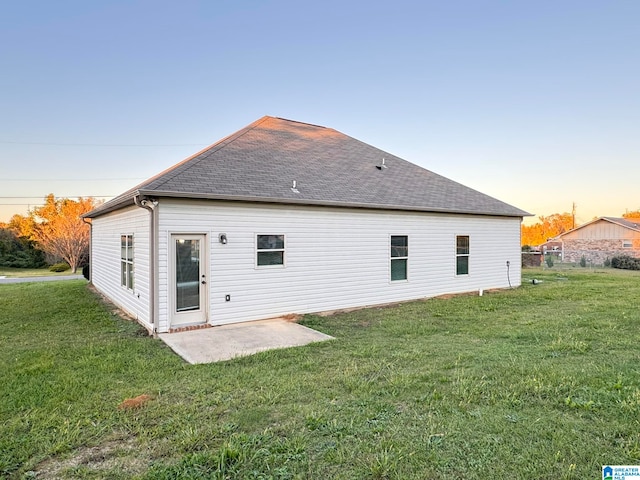 back house at dusk with a yard and a patio