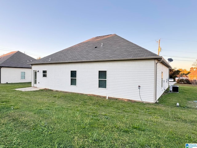 back of property featuring a yard and central AC