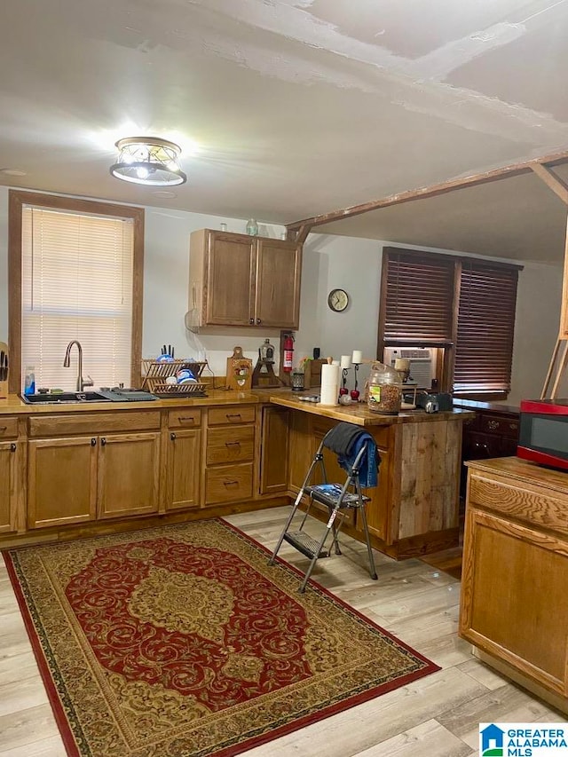 kitchen with kitchen peninsula, light wood-type flooring, and sink