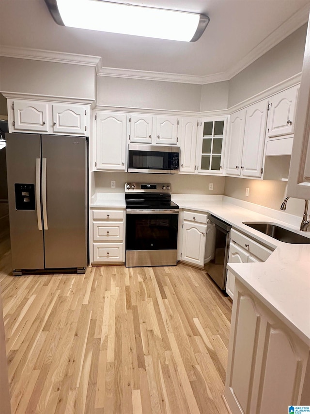 kitchen featuring white cabinets, stainless steel appliances, crown molding, and sink