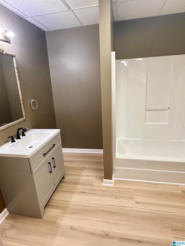 bathroom featuring vanity, hardwood / wood-style flooring, bathing tub / shower combination, and a paneled ceiling