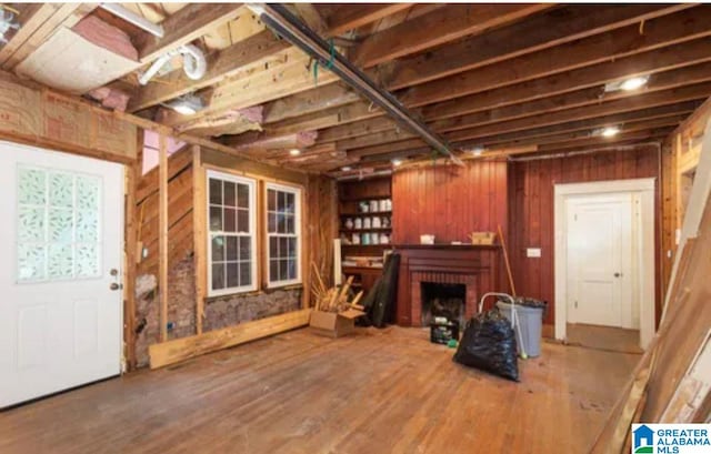 misc room featuring a fireplace, wood-type flooring, and wood walls