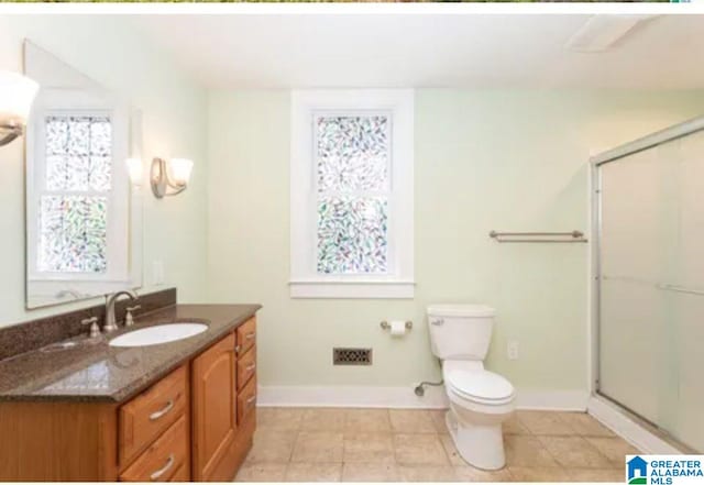 bathroom with tile patterned floors, toilet, vanity, and walk in shower