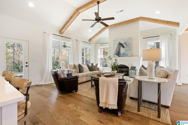 living room with vaulted ceiling with beams, light hardwood / wood-style flooring, a wealth of natural light, and ceiling fan