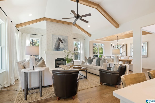 living room with vaulted ceiling with beams, plenty of natural light, light wood-type flooring, and ceiling fan with notable chandelier