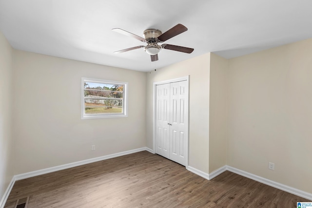 unfurnished bedroom featuring wood-type flooring, a closet, and ceiling fan