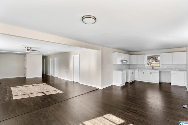 unfurnished living room featuring dark hardwood / wood-style flooring, ceiling fan, and sink