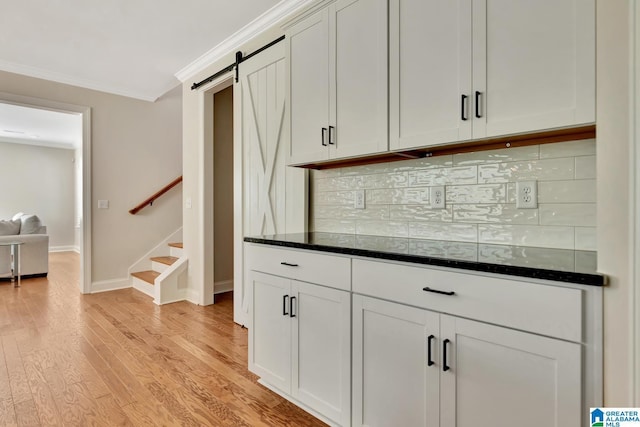 1114 Eagle Nest Cir, Birmingham, AL 35242 - kitchen featuring a barn door, ornamental molding, light wood-type flooring, baseboards, and white cabinets