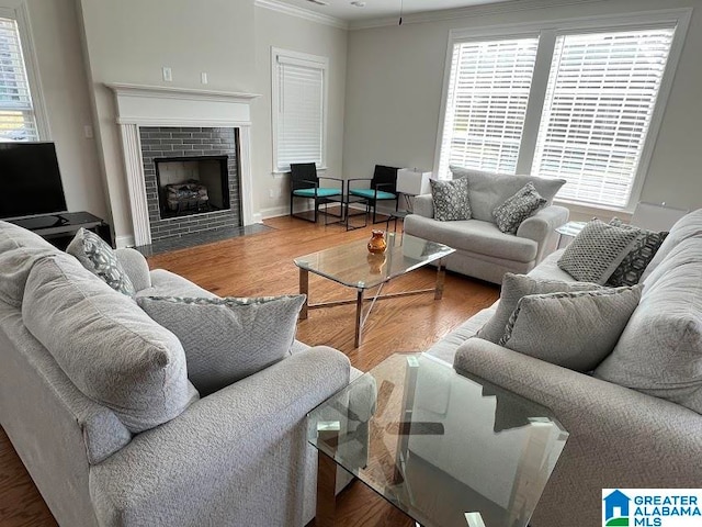 living room with crown molding, hardwood / wood-style floors, and a brick fireplace