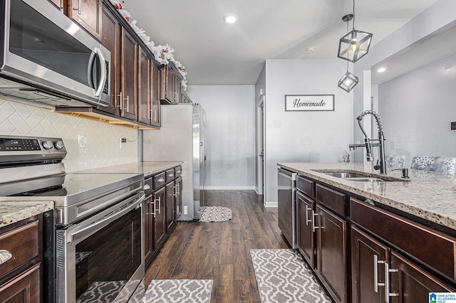 kitchen featuring sink, hanging light fixtures, stainless steel appliances, dark hardwood / wood-style floors, and dark brown cabinets