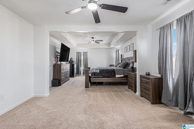 carpeted bedroom featuring a tray ceiling and ceiling fan