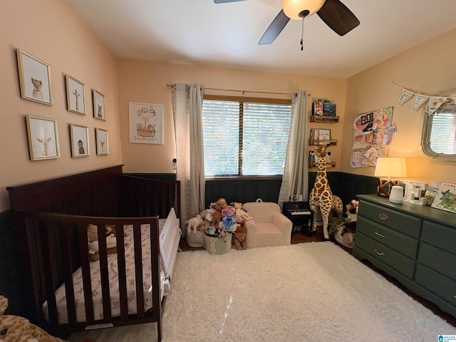 bedroom featuring ceiling fan and a crib