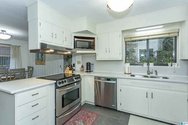 kitchen with white cabinets, sink, dark tile patterned floors, and stainless steel appliances