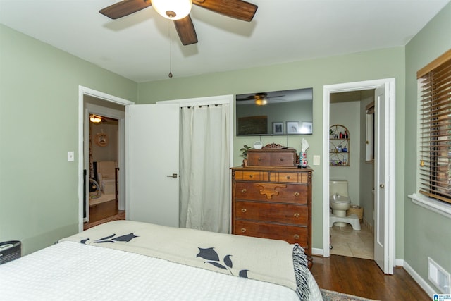 bedroom with ensuite bath, ceiling fan, and dark hardwood / wood-style floors