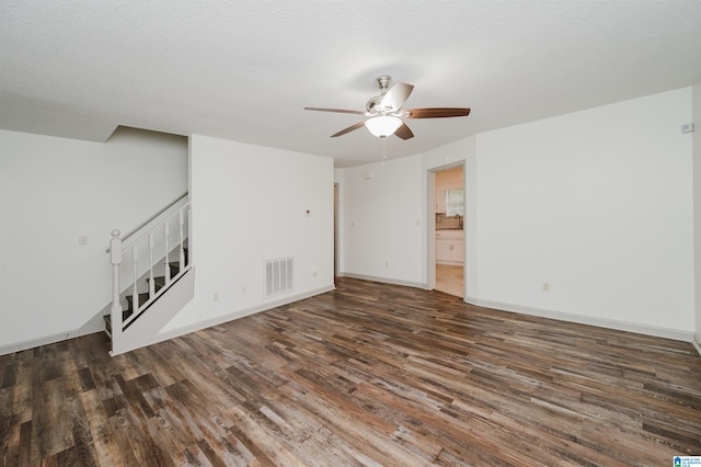 unfurnished living room with a textured ceiling, ceiling fan, and dark wood-type flooring