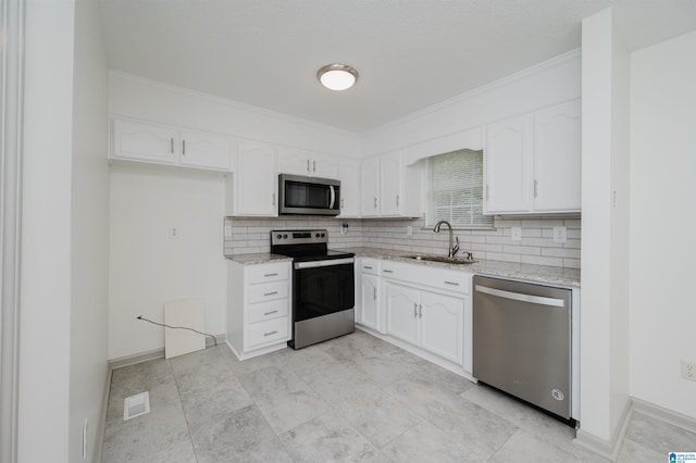 kitchen with sink, white cabinets, ornamental molding, and appliances with stainless steel finishes