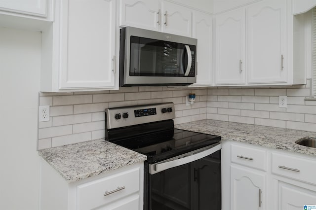 kitchen featuring light stone countertops, stainless steel appliances, white cabinetry, and tasteful backsplash