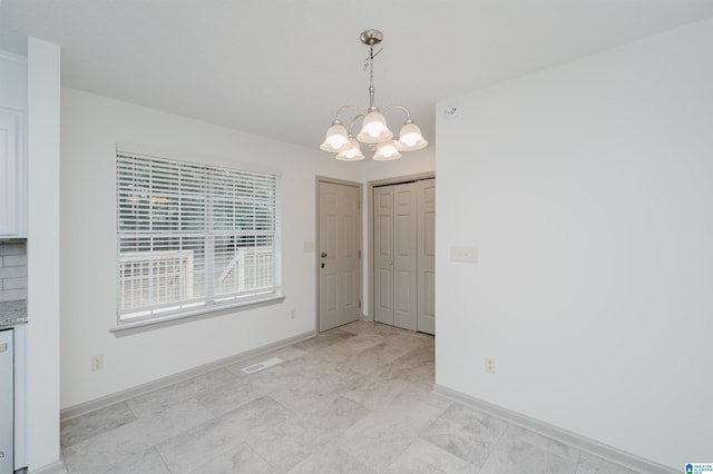 unfurnished dining area featuring a notable chandelier