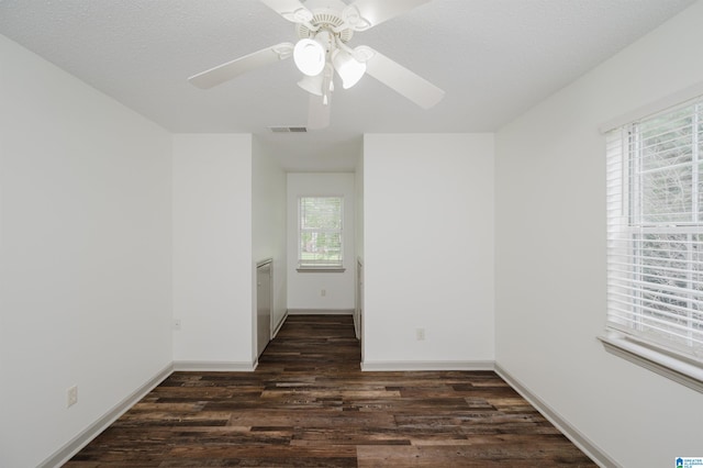 unfurnished room featuring a textured ceiling, dark hardwood / wood-style flooring, ceiling fan, and a healthy amount of sunlight