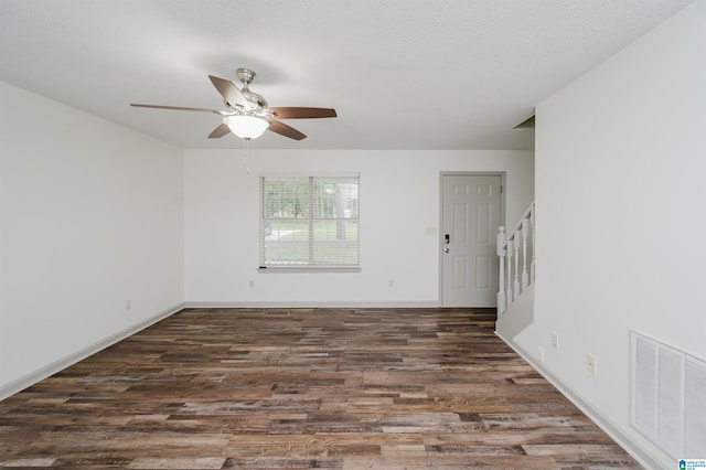 spare room with dark hardwood / wood-style floors, ceiling fan, and a textured ceiling