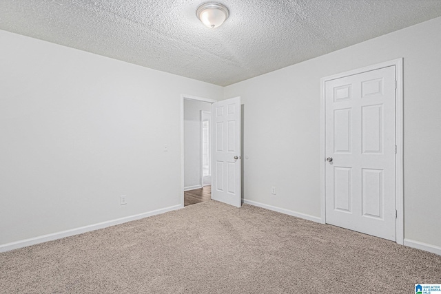 carpeted empty room featuring a textured ceiling