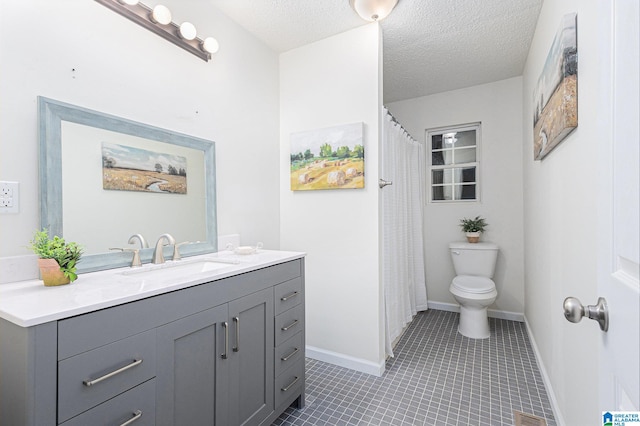 bathroom with tile patterned flooring, vanity, a textured ceiling, and toilet