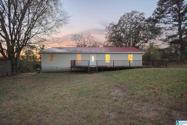 back house at dusk featuring a deck and a yard