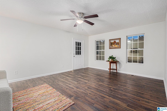 empty room featuring dark hardwood / wood-style floors, ceiling fan, and a textured ceiling