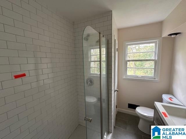 bathroom featuring tile patterned floors, vanity, toilet, and a shower with shower door