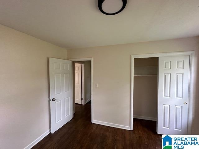 unfurnished bedroom with dark hardwood / wood-style flooring and a closet