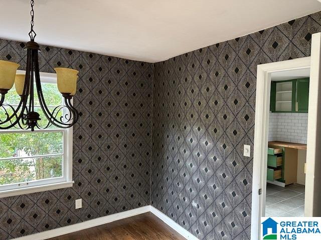 unfurnished room with a chandelier, hardwood / wood-style floors, plenty of natural light, and tile walls