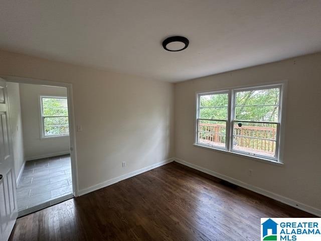 spare room with a healthy amount of sunlight and dark hardwood / wood-style floors