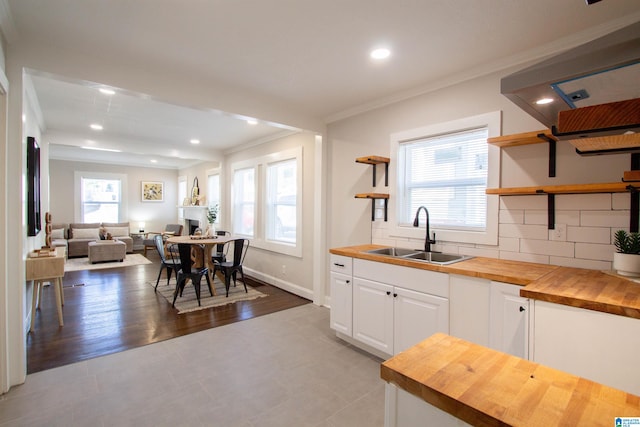 kitchen with wood counters, backsplash, sink, light hardwood / wood-style flooring, and white cabinetry