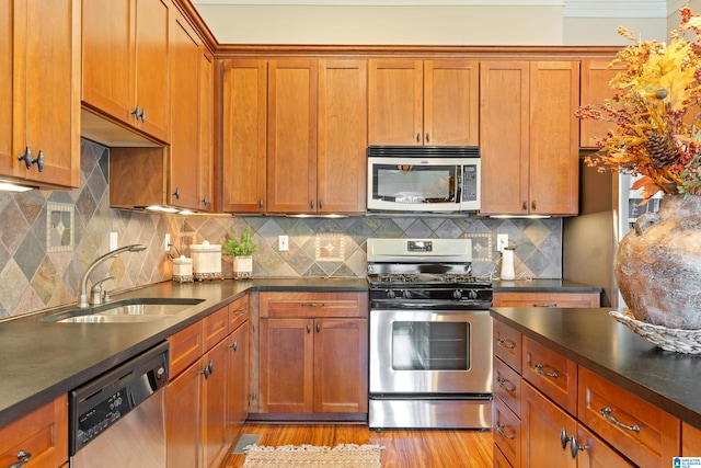 kitchen featuring appliances with stainless steel finishes, tasteful backsplash, light hardwood / wood-style flooring, and sink