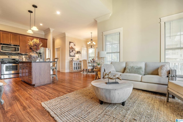 living room featuring crown molding, dark wood-type flooring, and a notable chandelier